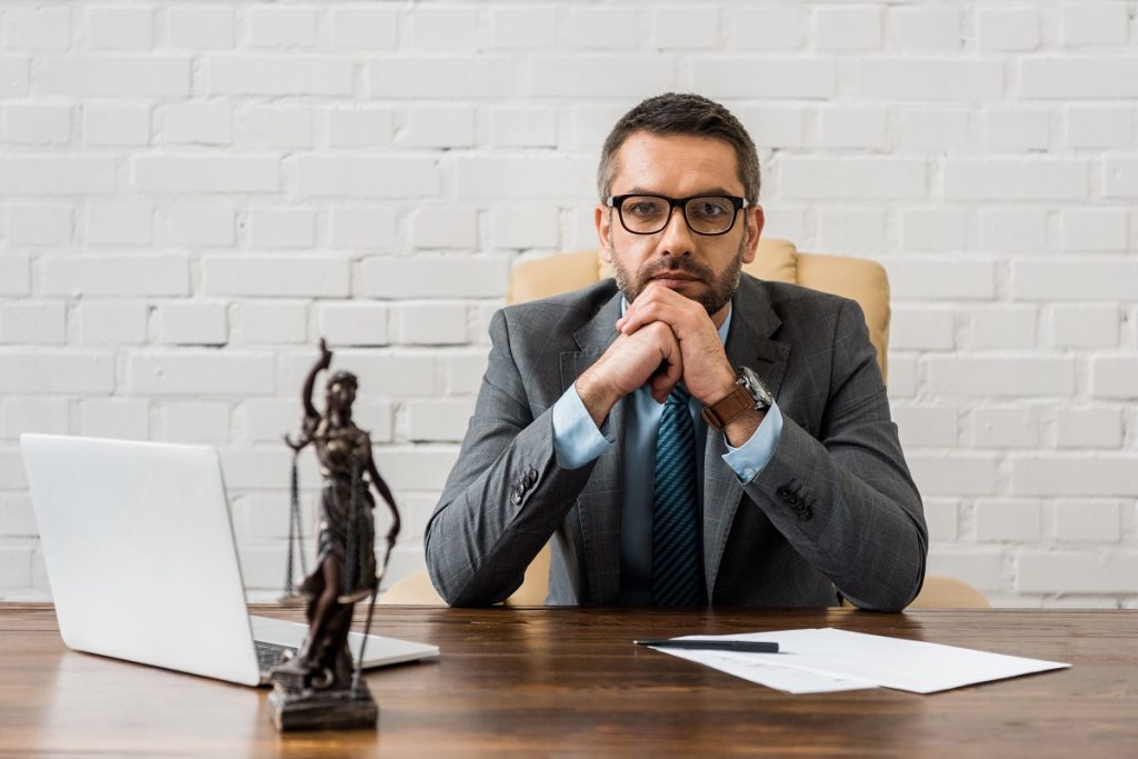 A lawyer sitting at a desk with a statue of Lady Justice